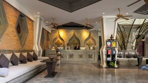 A spacious lobby with a reception desk, sofas, and a decorative wall with geometric patterns. - Central Suite Residence (Siem Reap)