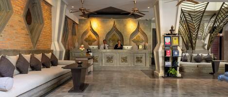 A spacious lobby with a reception desk, sofas, and a decorative wall with geometric patterns.