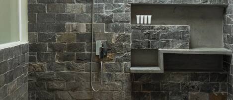 A stone-walled shower with a built-in shelf and a window above.