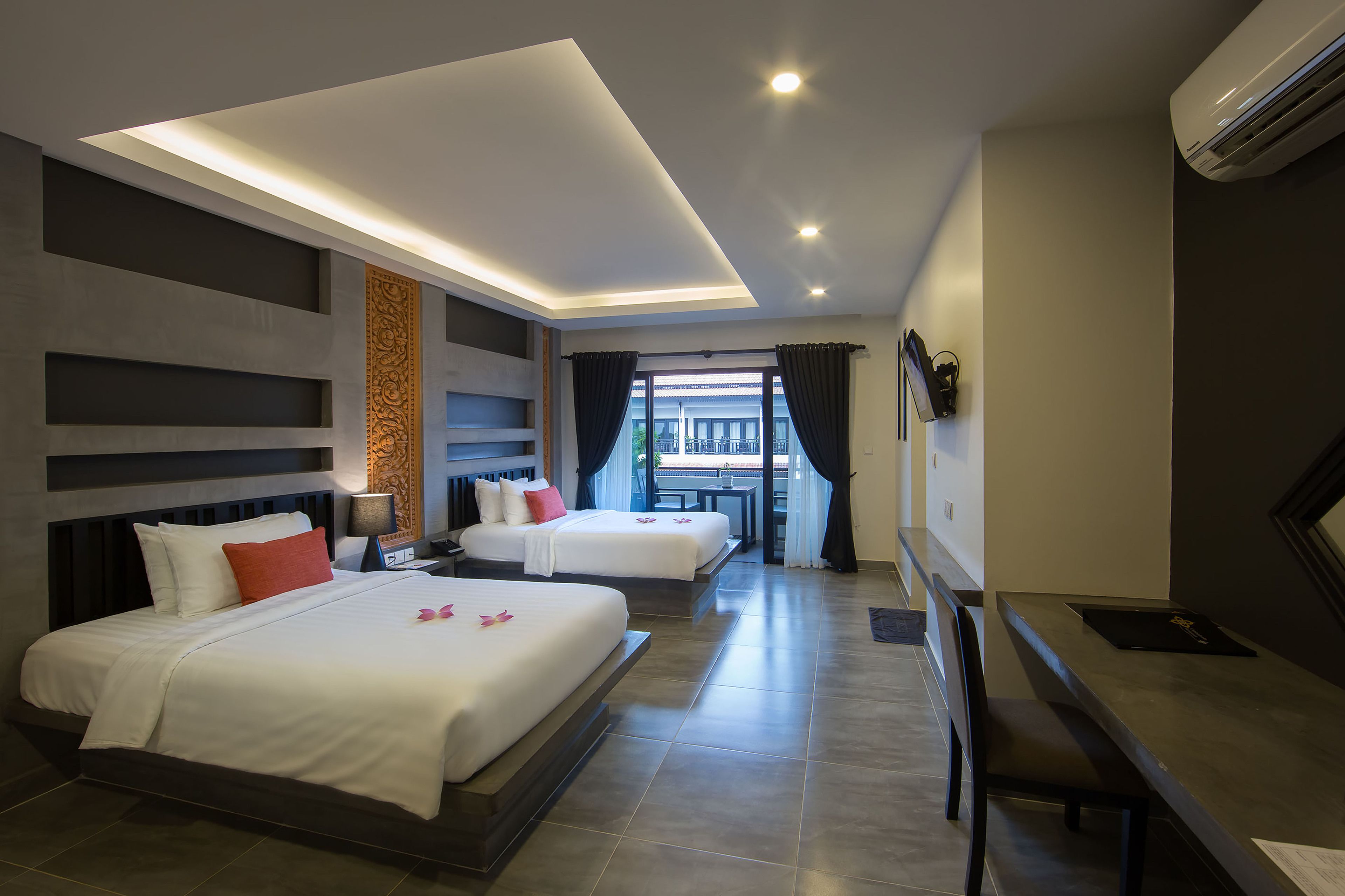 Une chambre d’hôtel moderne avec deux lits, un bureau et une vue sur l’extérieur.