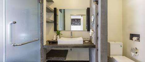 Une salle de bain moderne avec un lavabo blanc, un plan de toilette noir et des toilettes.