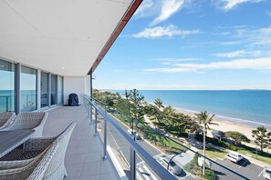 A balcony with wicker furniture overlooking a beach and ocean. - Salt Apartments Yeppoon (Yeppoon)