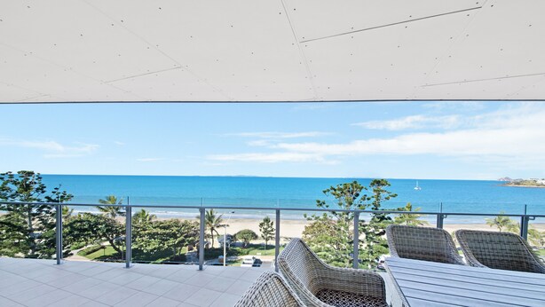 A balcony with wicker furniture overlooking a beach and ocean. - Salt Apartments Yeppoon (Yeppoon)