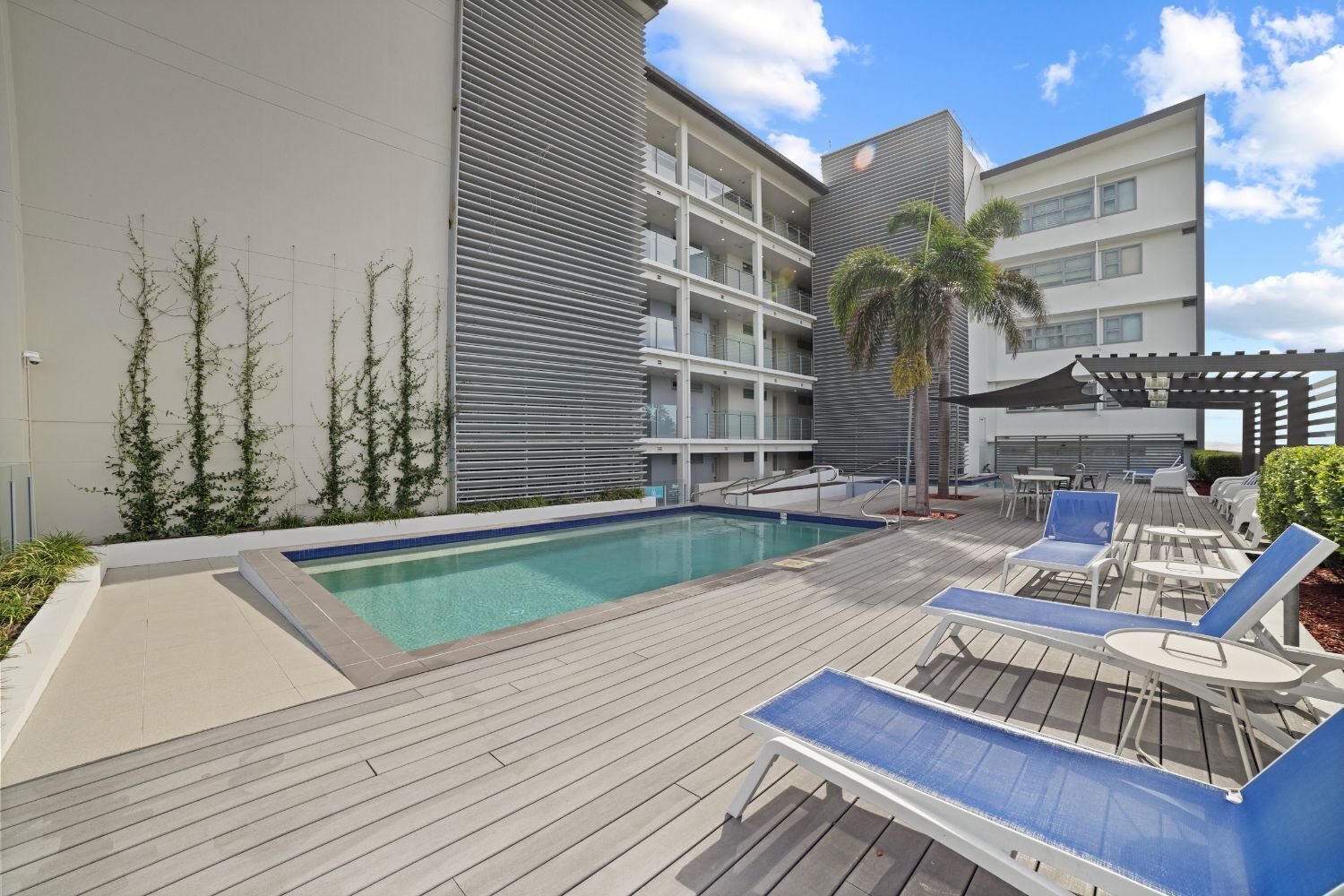 Un hotel moderno con piscina, mobiliario exterior y un edificio de varios pisos.