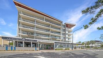 A multi-story hotel with balconies, a prominent entrance, and a clear sky.