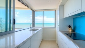 A modern kitchen with a large window offering a view of the ocean. - Salt Apartments Yeppoon (Yeppoon)