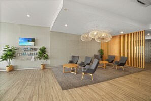 Una moderna zona de recepción con televisor de pantalla plana, mobiliario de madera e iluminación decorativa.