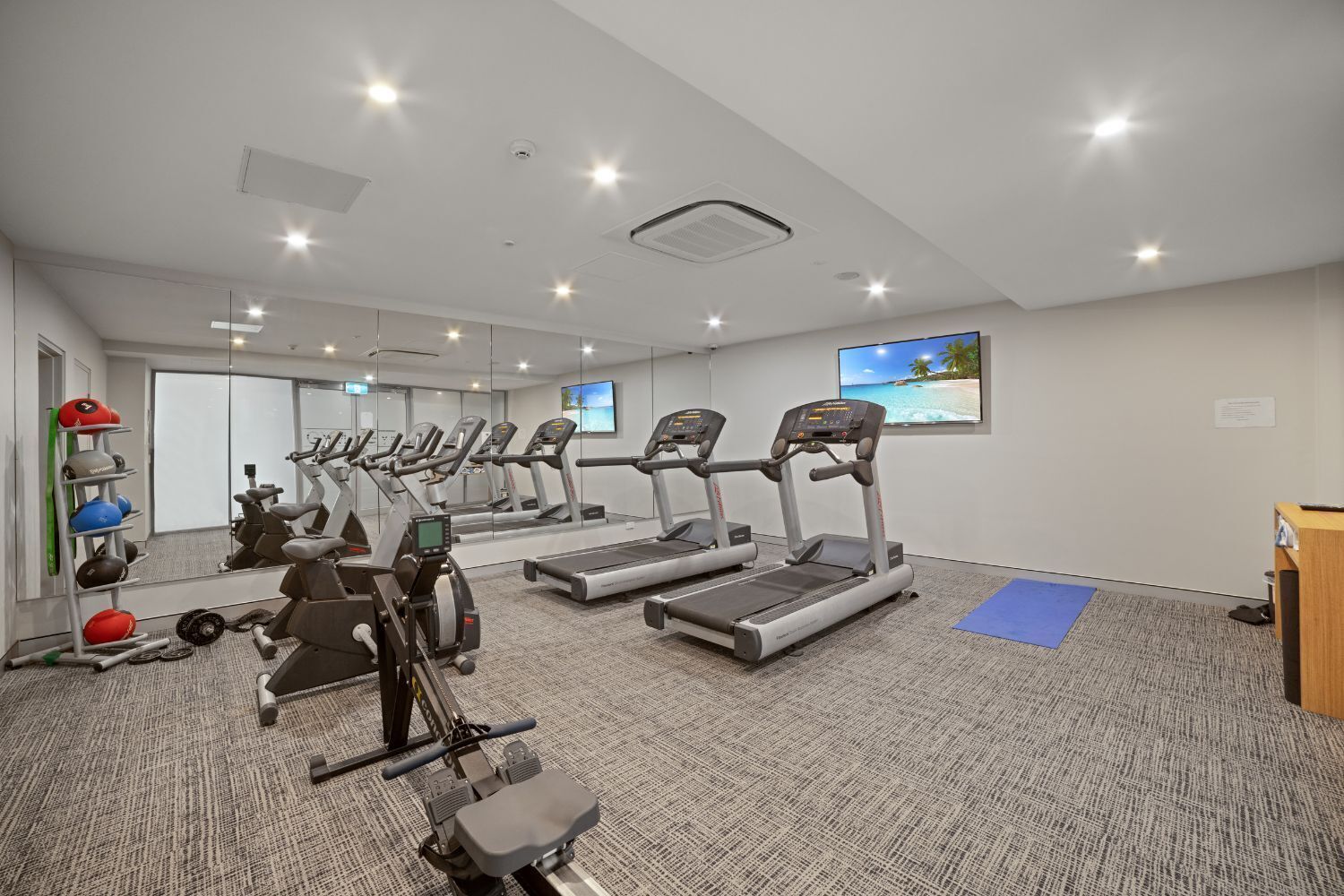 A gym with treadmills, a rowing machine, and a weight rack.