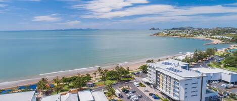 A coastal hotel with a beach view, parking, and modern architecture.