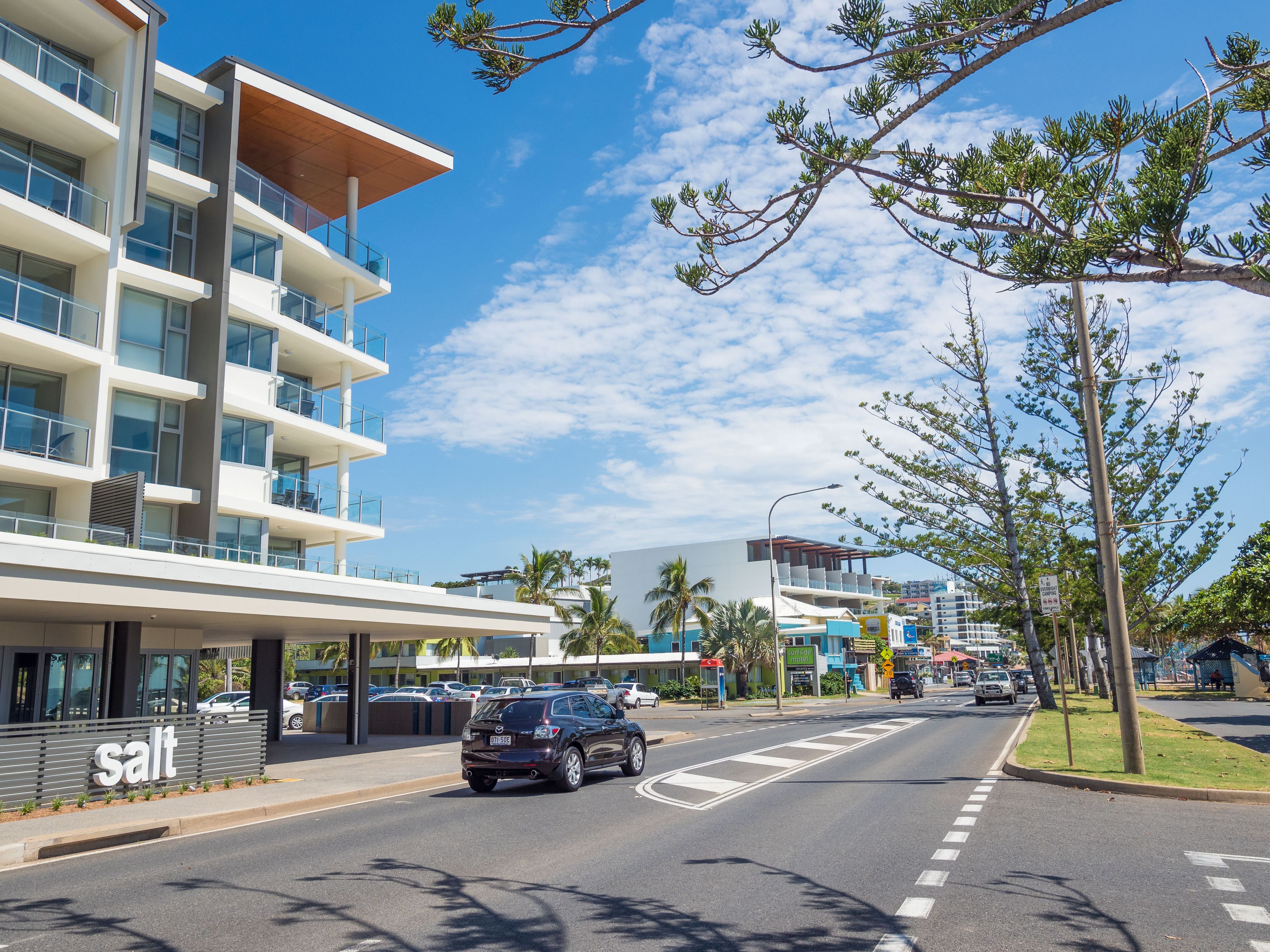 A modern hotel with multiple floors, a covered entrance, and a parking area.