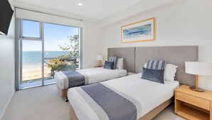 A bedroom with two beds, a large window with a view of the beach, a flat-screen TV, and a framed painting on the wall. - Salt Apartments Yeppoon (Yeppoon)