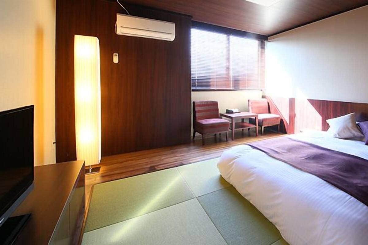 A hotel room with a bed, a desk, a chair, and a TV.