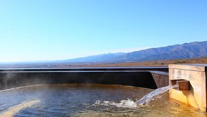 A hot spring with a wooden bench and a view of mountains in the background. - Nasu Ichiya Hotel (Nasu)