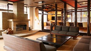 A spacious living area with a fireplace, a sofa, a coffee table, and a view of the outdoor area. - Nasu Ichiya Hotel (Nasu)