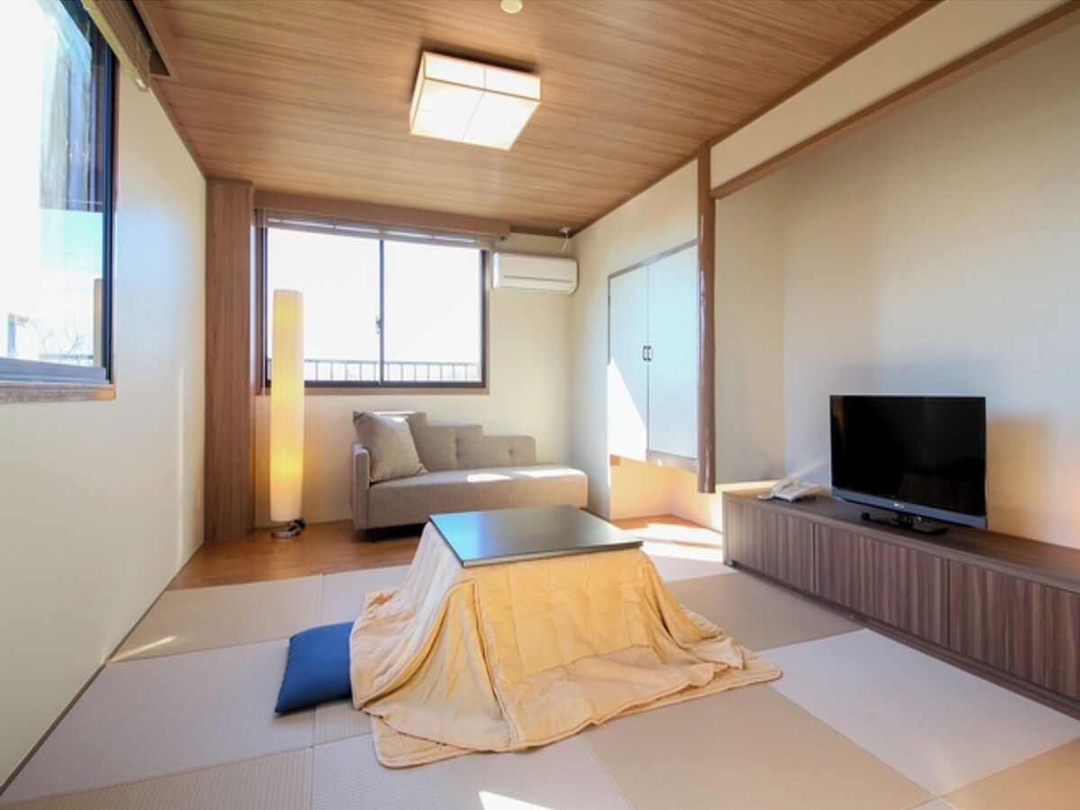 A modern living room with a sofa, a television, and tatami mats.