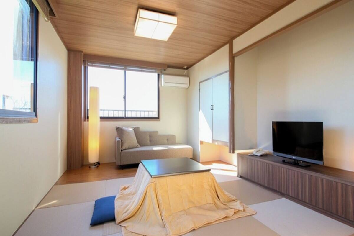 A modern living room with a sofa, a television, and tatami mats.