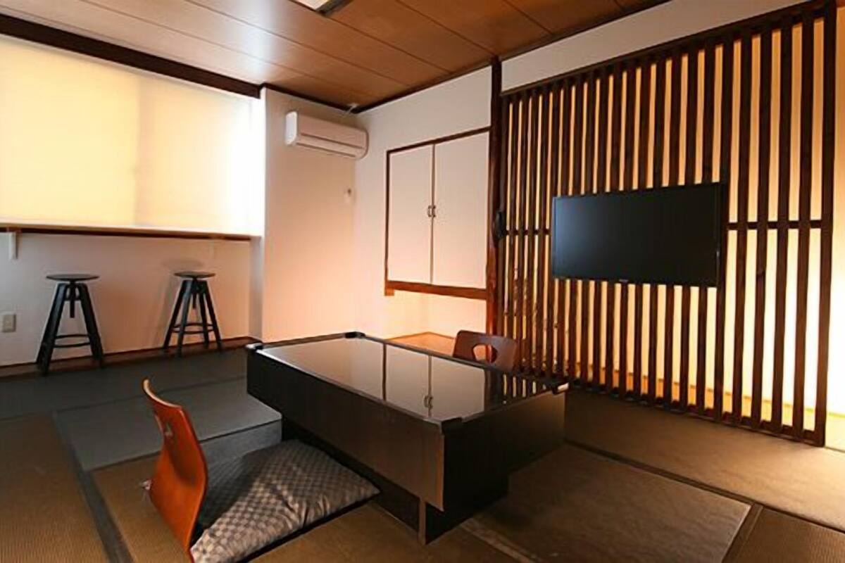 A modern room with a desk, two stools, a TV, and a sliding shoji screen.