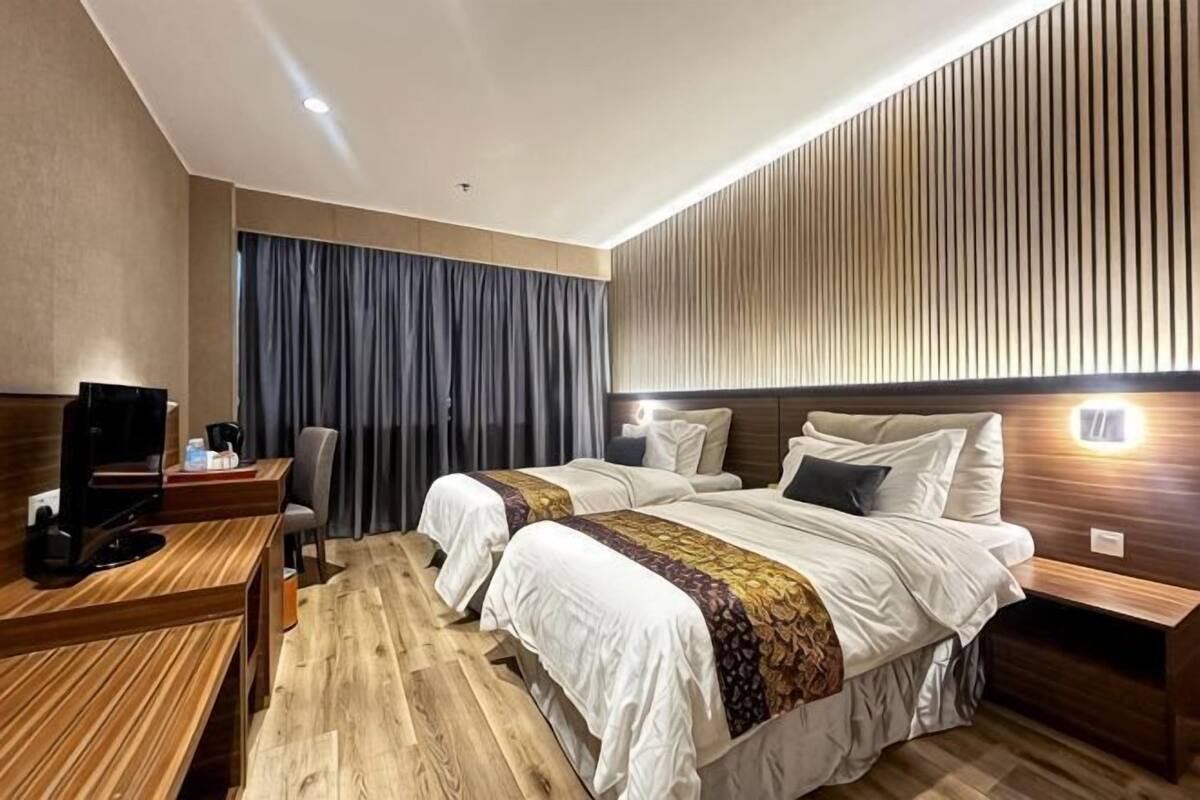 A hotel room with two beds, a desk with a computer, and a TV.