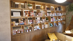 Une bibliothèque avec des étagères en bois remplies de livres et de mangas.