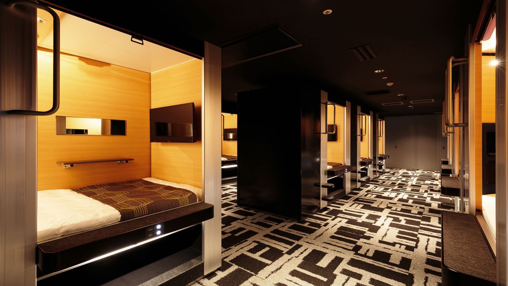 A hotel room with a bed, a TV, a mirror, and a bathroom with a shower and toilet.