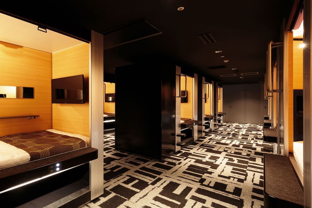 Ein Hotelzimmer mit Bett, Fernseher, Spiegel und einem Badezimmer mit Dusche und Toilette.