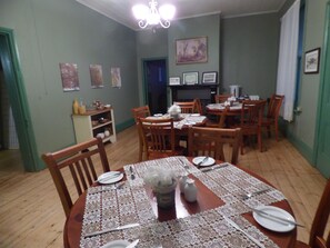 A dining area with a round table set for four, surrounded by wooden chairs. There is a small cabinet with dishes and condiments to the left. - Tenterfield Lodge and Caravan Park (Tenterfield)