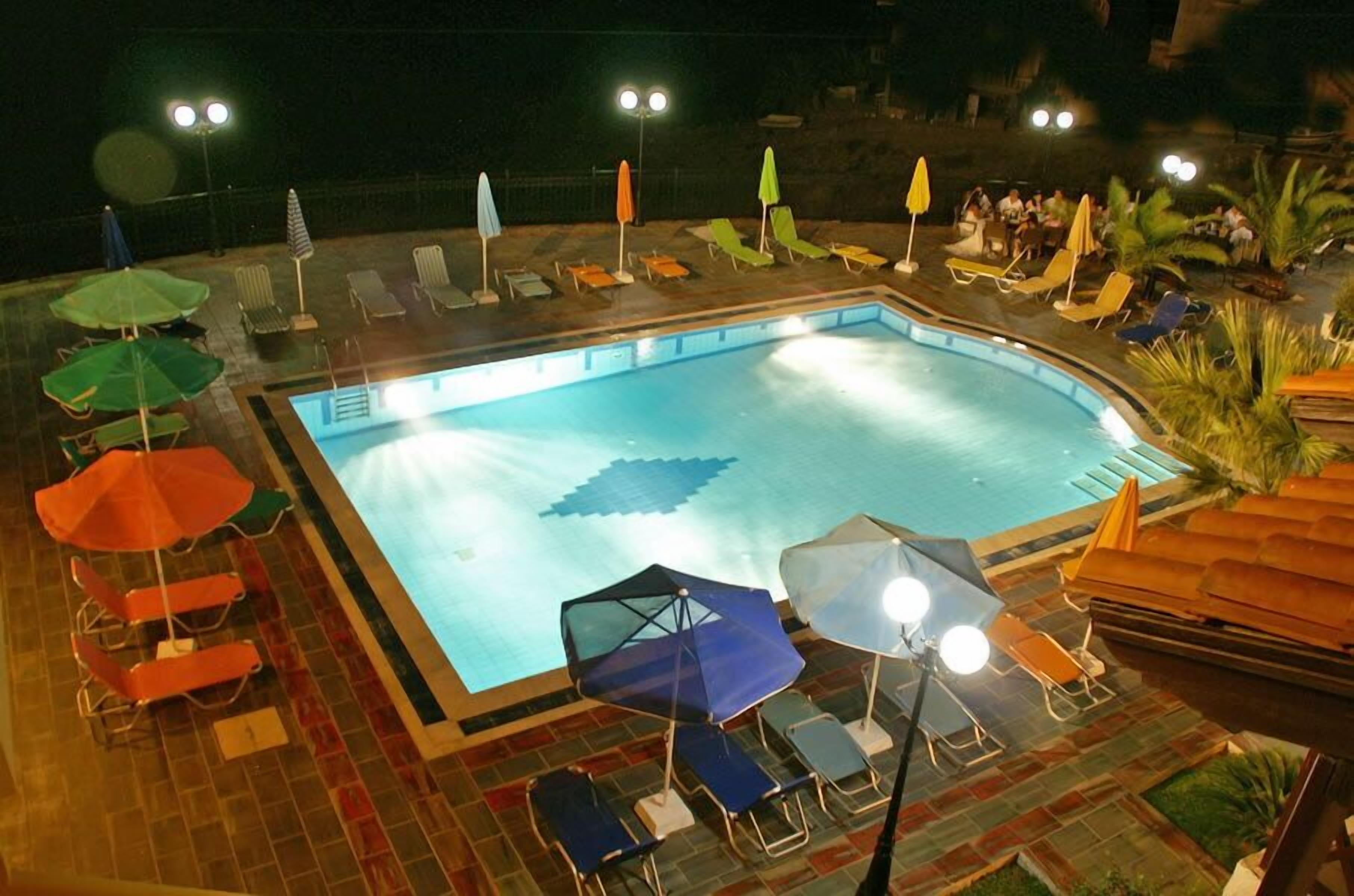 A swimming pool with lounge chairs and umbrellas, surrounded by a tiled deck.