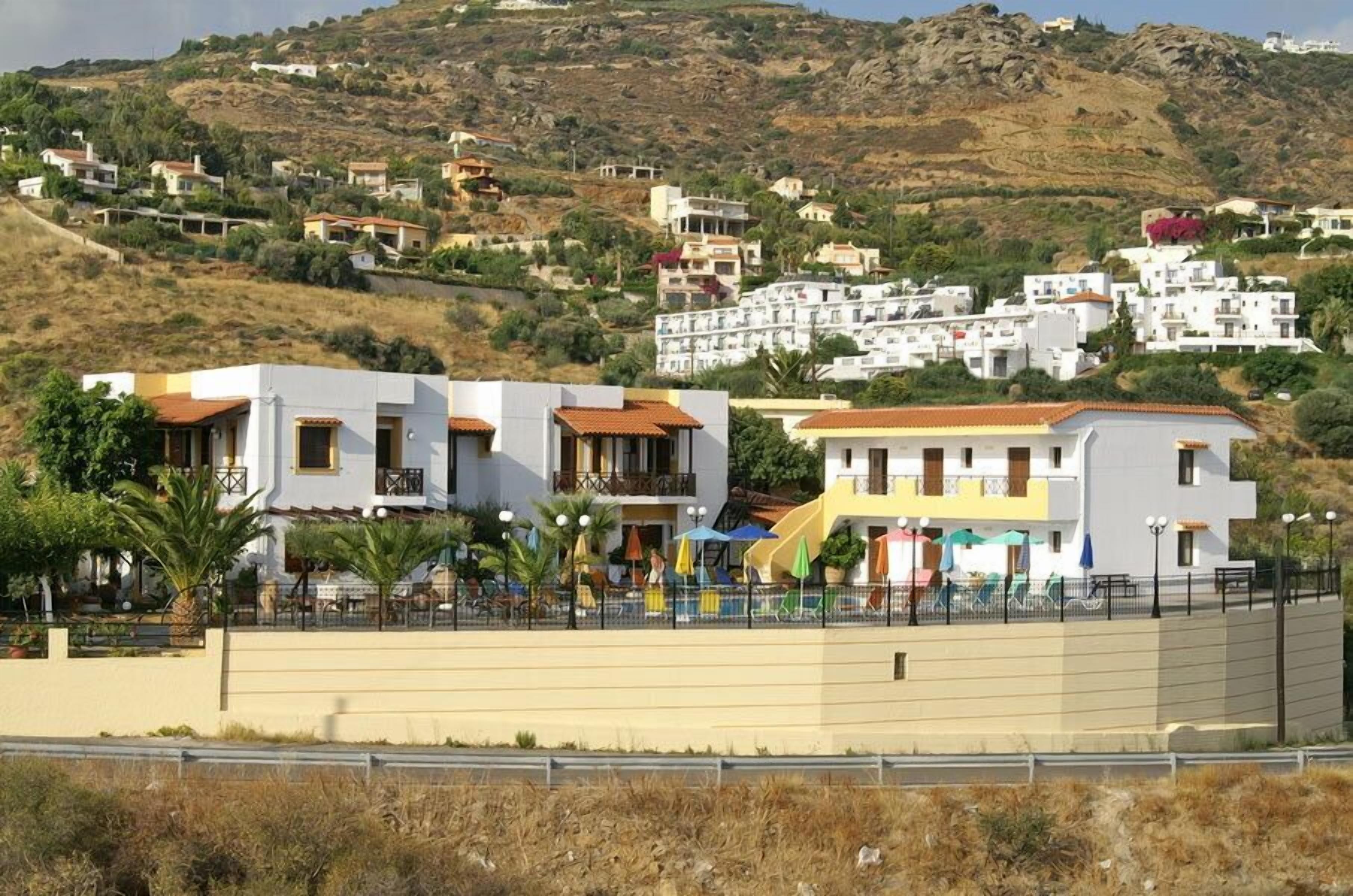 A coastal residential area with modern houses, a sandy beach, and a hilly backdrop.
