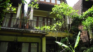 A traditional two-story building with a balcony, surrounded by lush greenery. - Villa Jineng Ubud Bali (Ubud)