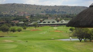 Un campo de golf con un edificio de techo de paja al fondo.