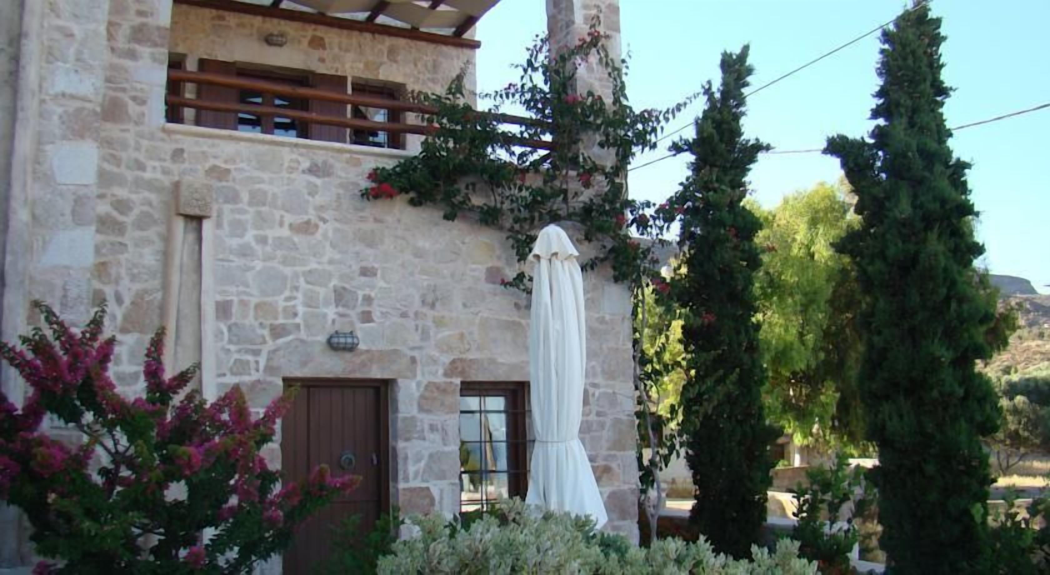 A stone building with a wooden balcony, a brown door, and a white cloth draped over a structure.