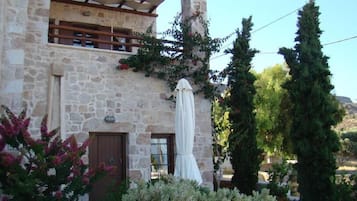 A stone building with a wooden balcony, a brown door, and a white cloth draped over a structure.