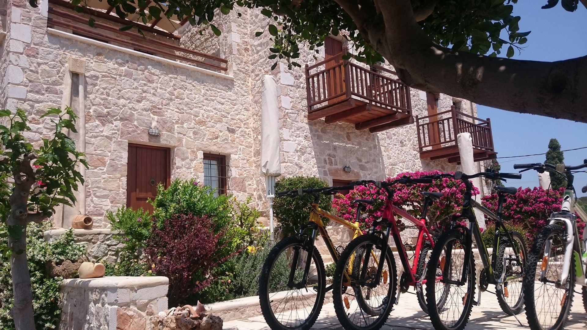 A stone building with balconies, a bicycle parked in front, and surrounding greenery.