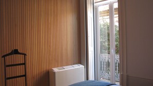 A room with a radiator, a chair, and a window with a view of greenery outside. - Koolhouse Porto (Porto)