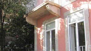 A building with a balcony, a set of stairs leading to the entrance, and a door with a window. - Koolhouse Porto (Porto)