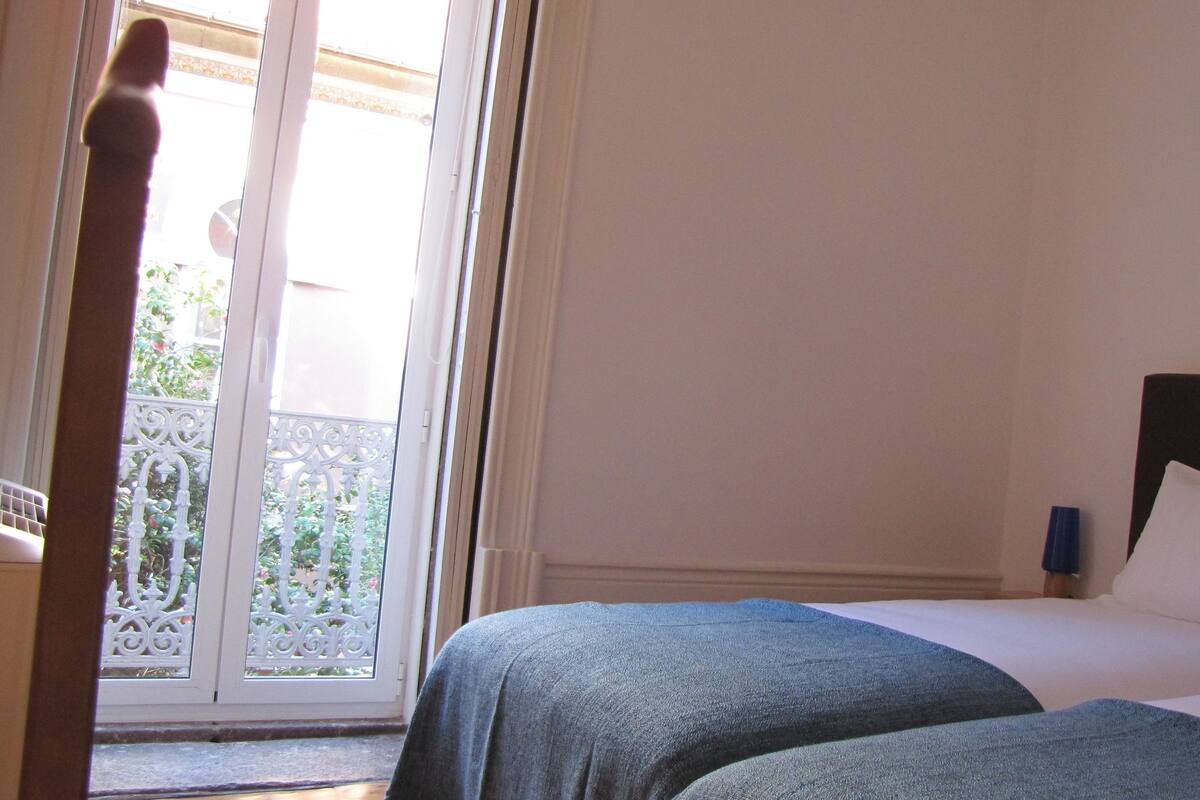A bedroom with a bed, a nightstand, and a view of a balcony.