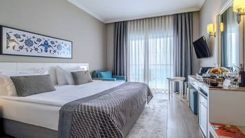 Una habitación de hotel con una cama, un escritorio con computadora, un televisor y una ventana con cortinas.