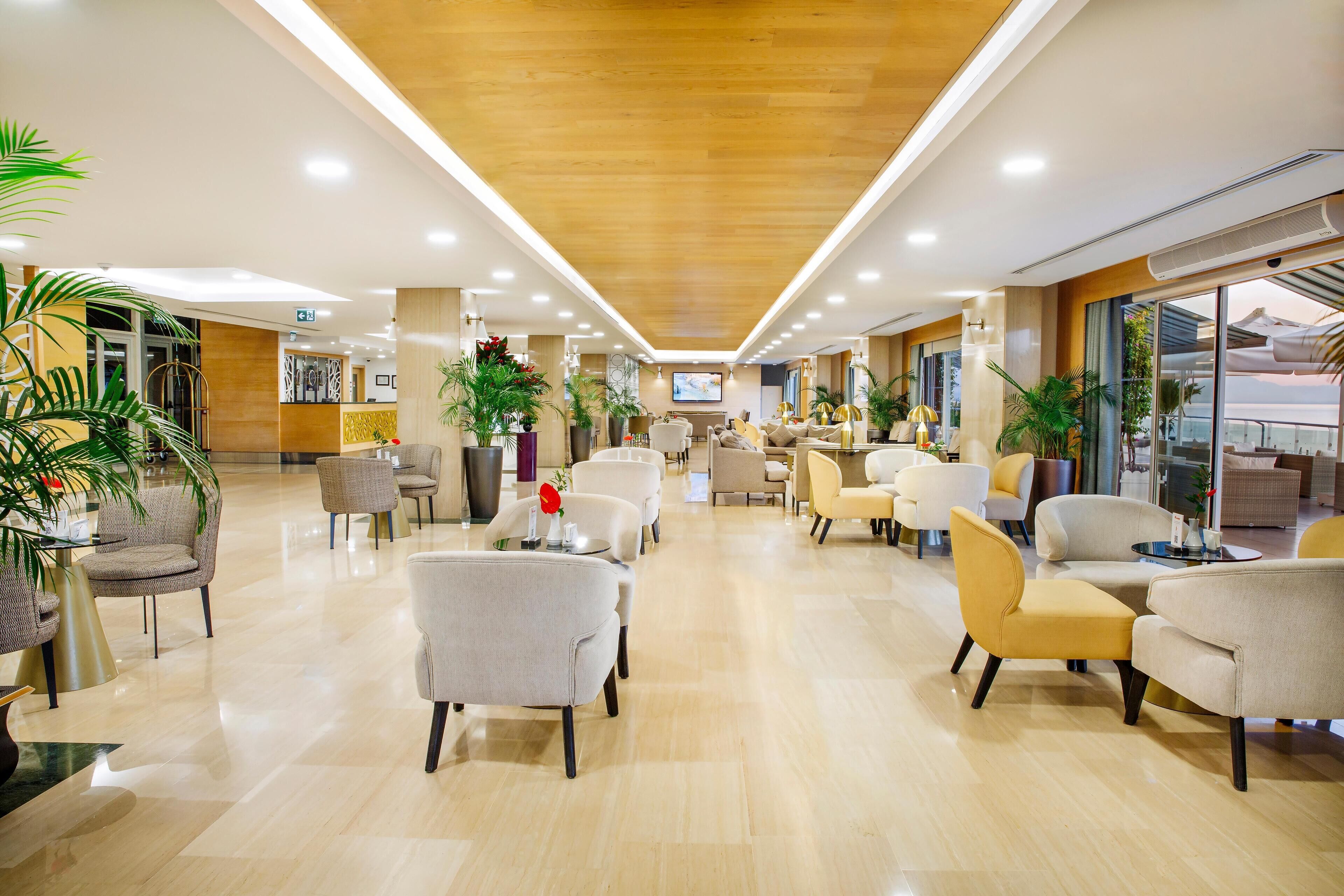 A spacious lobby with a wooden ceiling, multiple seating areas, and large windows offering views.