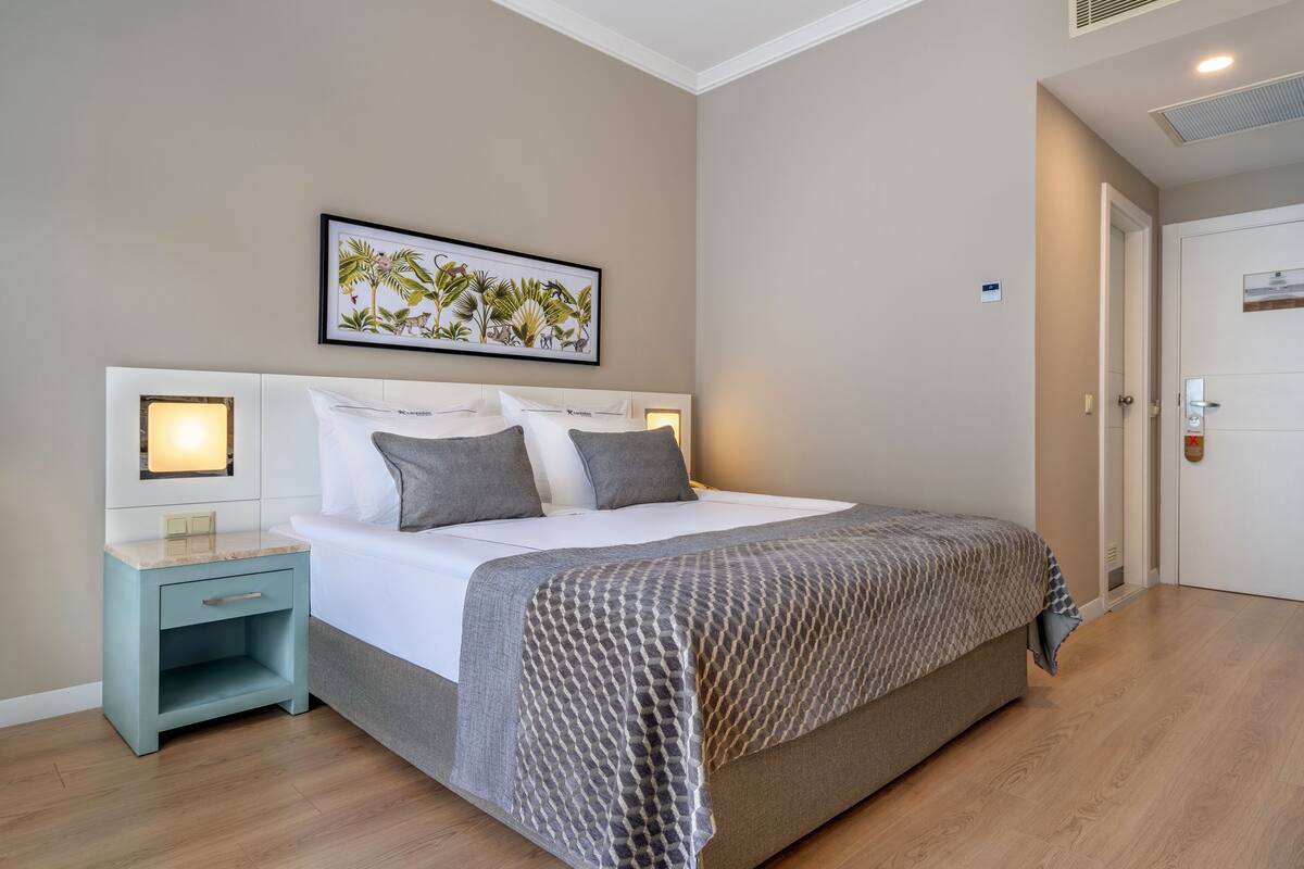 A bedroom with a bed, nightstand, and a framed botanical print on the wall.