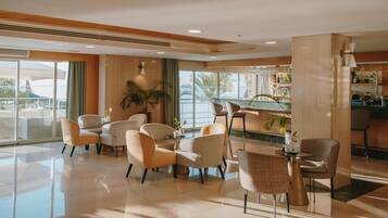Un moderno vestíbulo de hotel con una zona de estar, un bar y vistas al exterior.
