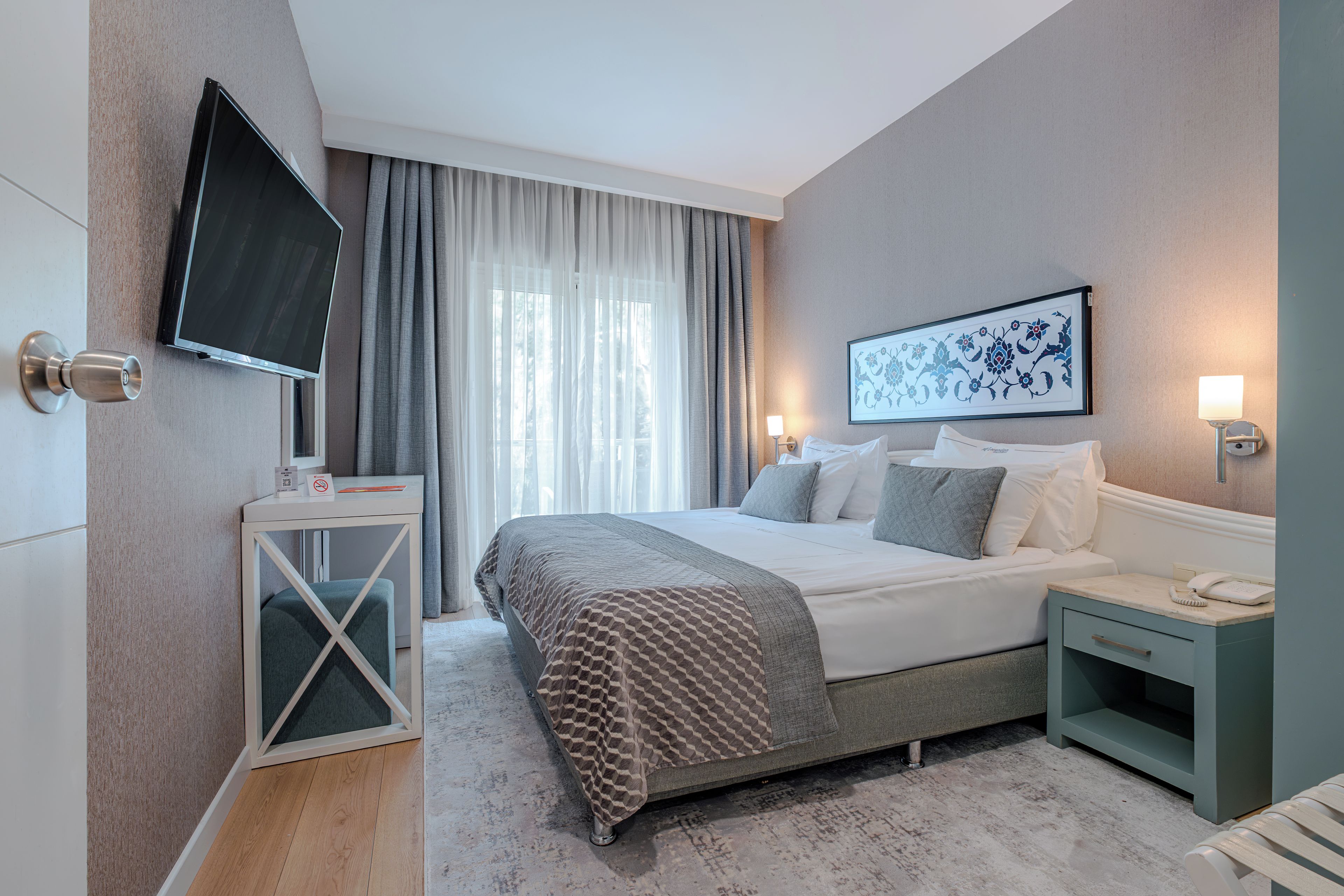 Una habitación de hotel moderna con una cama, una mesita de noche y un televisor de pantalla plana montado en la pared.