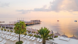 Un resort con tumbonas, sombrillas y un muelle que se adentra en aguas tranquilas.