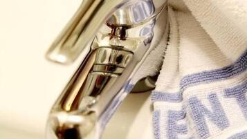 A bathroom sink with a chrome faucet and a white towel with blue stripes.