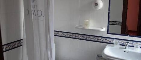 A bathroom with a shower curtain, toilet, sink, and mirror.