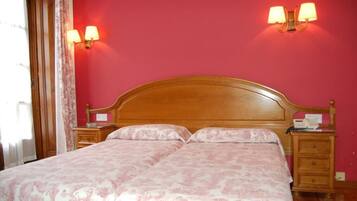 A double bed with a wooden headboard, two bedside tables with lamps, and a red wall.
