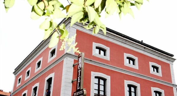 Un edificio rojo con varias ventanas y un cartel que dice "HOTEL PUENTE".