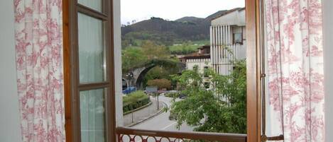 Un balcón con vista a una calle, un puente y edificios al fondo.