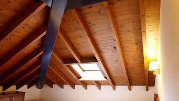 A room with a sloped wooden ceiling, a skylight, and a lamp on the right.