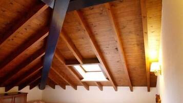 A room with two beds, wooden beams on the ceiling, and a red carpet.