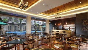 Un grand espace intérieur aménagé avec plusieurs tables et chaises, un coin bar et une vue sur une piscine à l’extérieur.